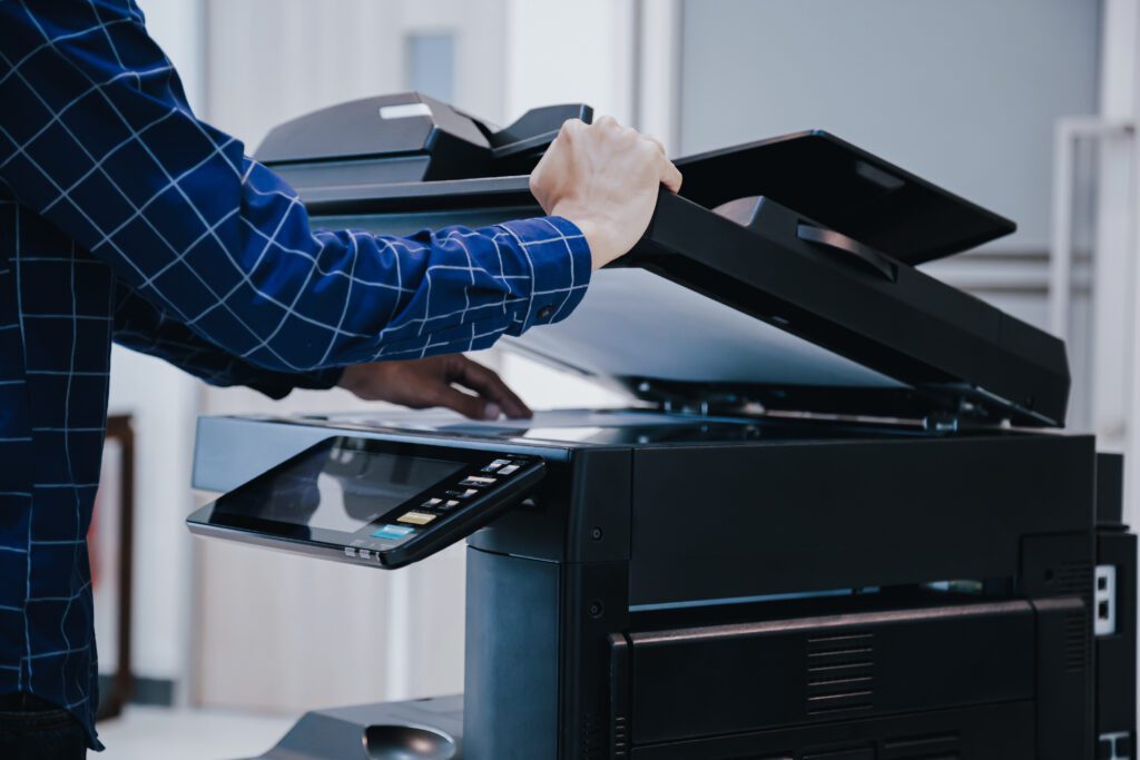 Impression : homme en bureau appuyant sur le bouton copier d'une machine à photocopier.